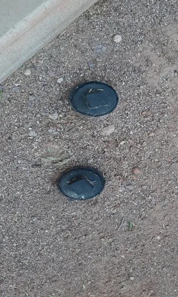 Pair of bidirectional sewer cleanout caps set flush in the ground beside a concrete walkway