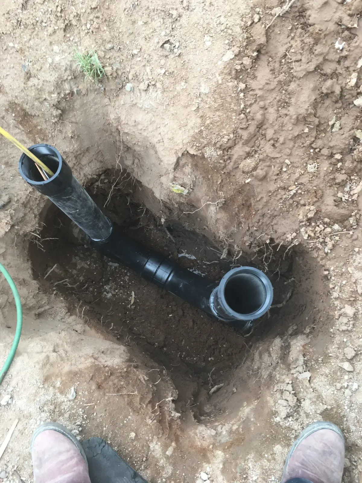 Two-way cleanout fitting with riser installed on an excavated sewer line before the trench is filled