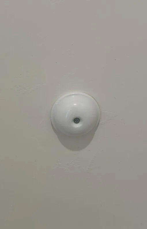 Round white cleanout cover plate mounted on an interior wall