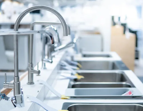 Showroom display row of stainless steel sinks and gooseneck faucets