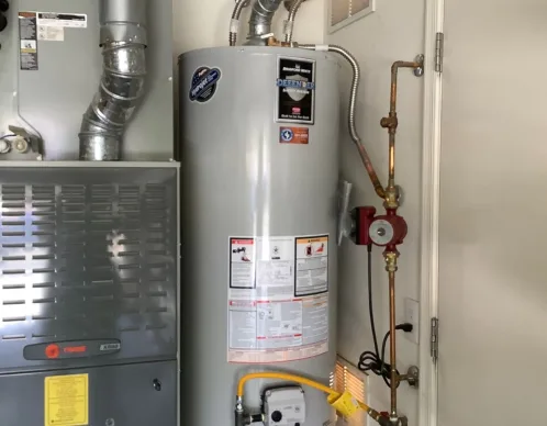 Tank water heater installed in a utility closet beside a furnace with copper piping