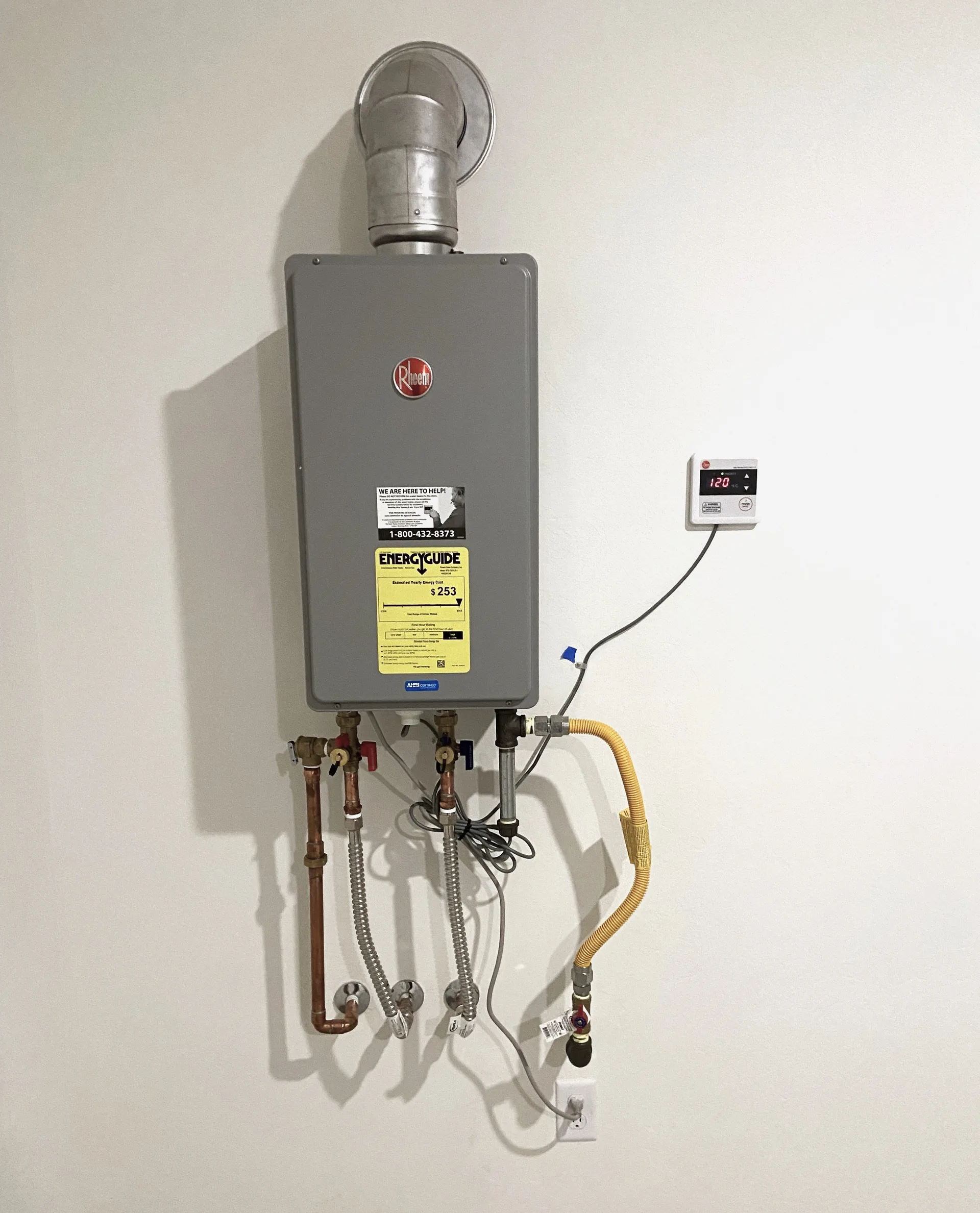 Gas tankless water heater installed on a wall with vent pipe and water line connections